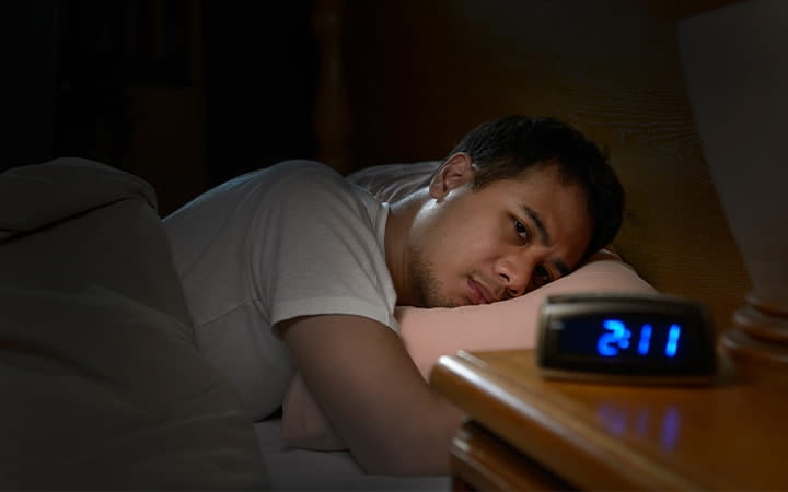A man suffering from insomnia lying in bed