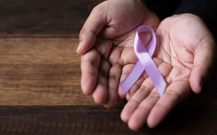 Close up of hands holding the testicular cancer ribbon