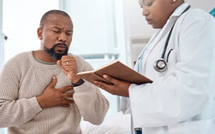 A mature man coughing during a consultation with a doctor in a clinic