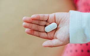 childs hand holding pill