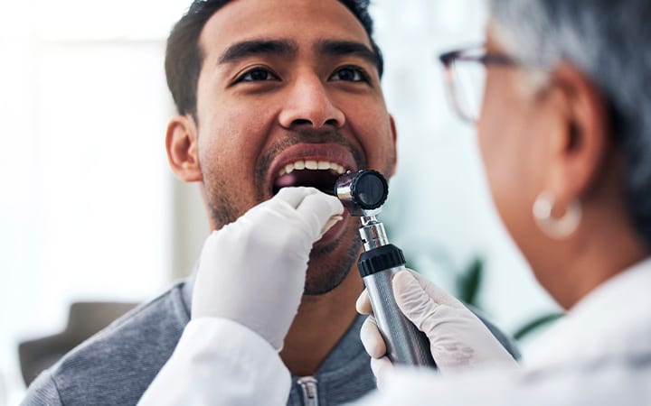 Doctor examines young mans mouth