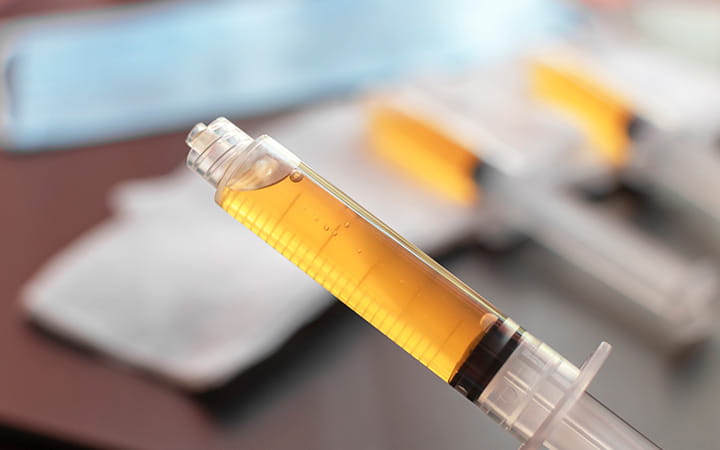 closeup of hypodermic syringe with yellow contents