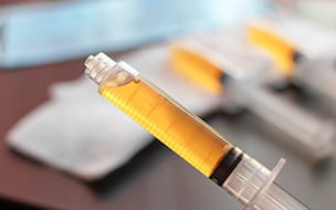 closeup of hypodermic syringe with yellow contents