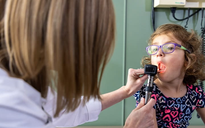 Pediatrician examines a young girls mouth
