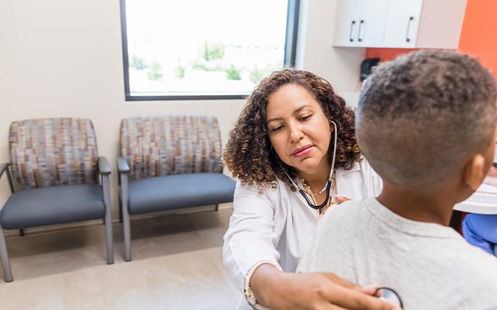 Pediatrician listens to young boys lungs