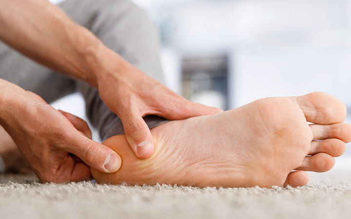 man's thumbs massaging his heel