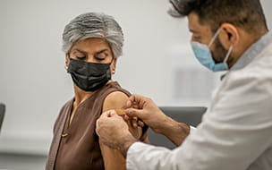 doctor putting bandaid on patient upper arm
