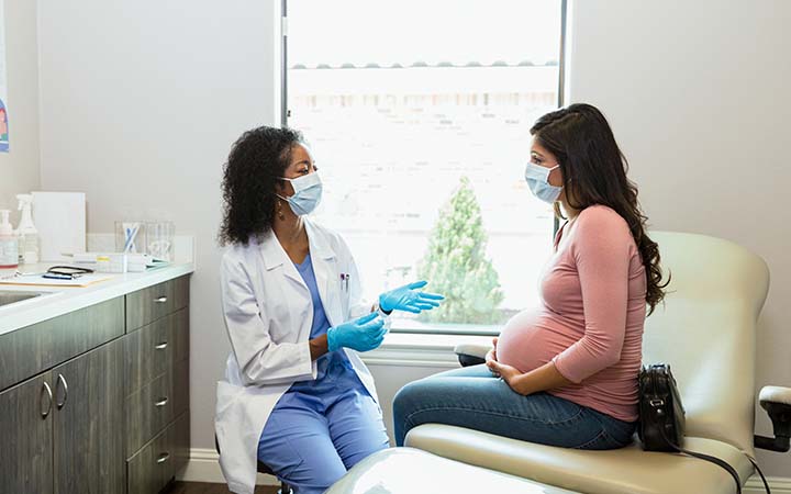female doctor talking with pregnant woman in exam room