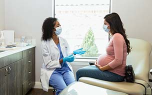 female doctor talking with pregnant woman in exam room
