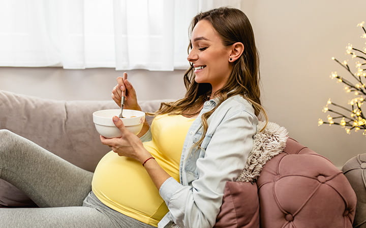 pregnant woman digging into a deep bowl with a spoon