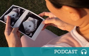 A pregnant woman holding an ultrasound photo