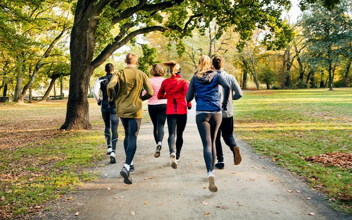 A rear view of joggers running through a park