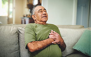 A senior man holds his chest in pain