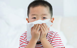 young child blowing his nose