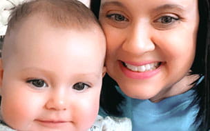 A smiling Jana Thomas at home with her infant daughter