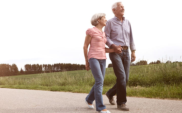 older man and woman walking down paved path