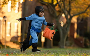 young boy in batman costume running with treat bag