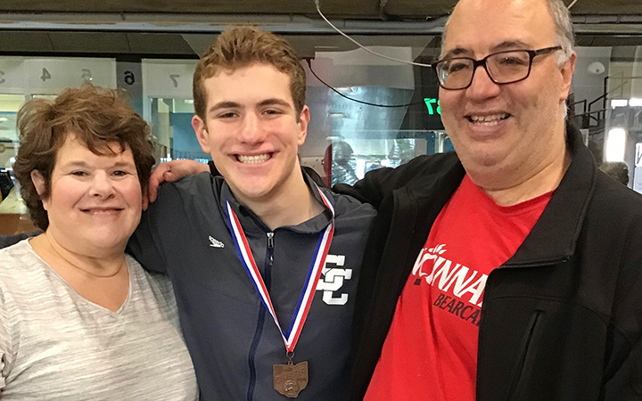 Josh with his parents at a diving competition after his continuous glucose monitor was placed.