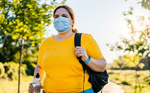 Overweight woman walking with mask and bottled water