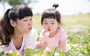 mom and girl blowing dandelions
