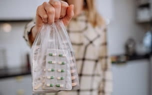 A woman holds a bag filled with expired pills ready to recycle
