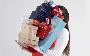 Woman carrying too many gift boxes