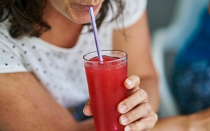 A woman drinking a tall glass of fruit juice