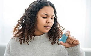 A woman taking her inhaler at home at the living room