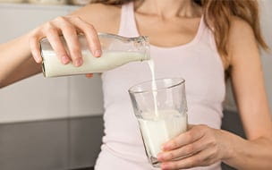woman pours milk into glass