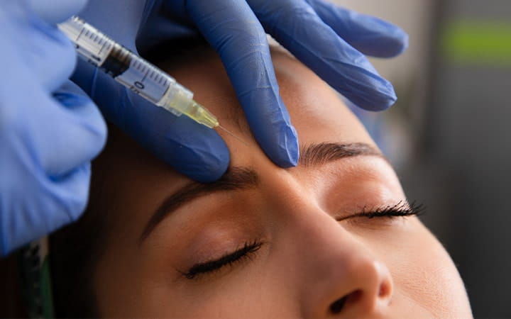 Woman receives Botox injection in forehead