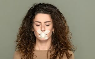 A young woman with closed eyes and taped lips