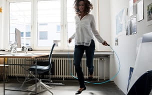 Businesswoman in office, training with skipping rope