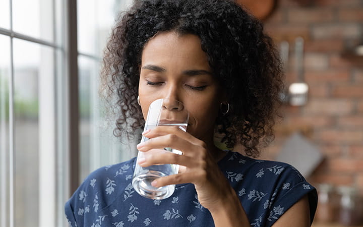 A young woman drinking mineral water in her kitchen