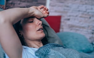 A woman suffering from a headache is lying in bed