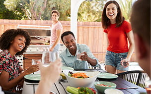 Young adult friends sitting outdoors for lunchtime barbecue