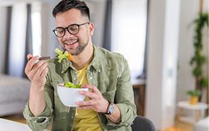 A happy young man eating a healthy salad