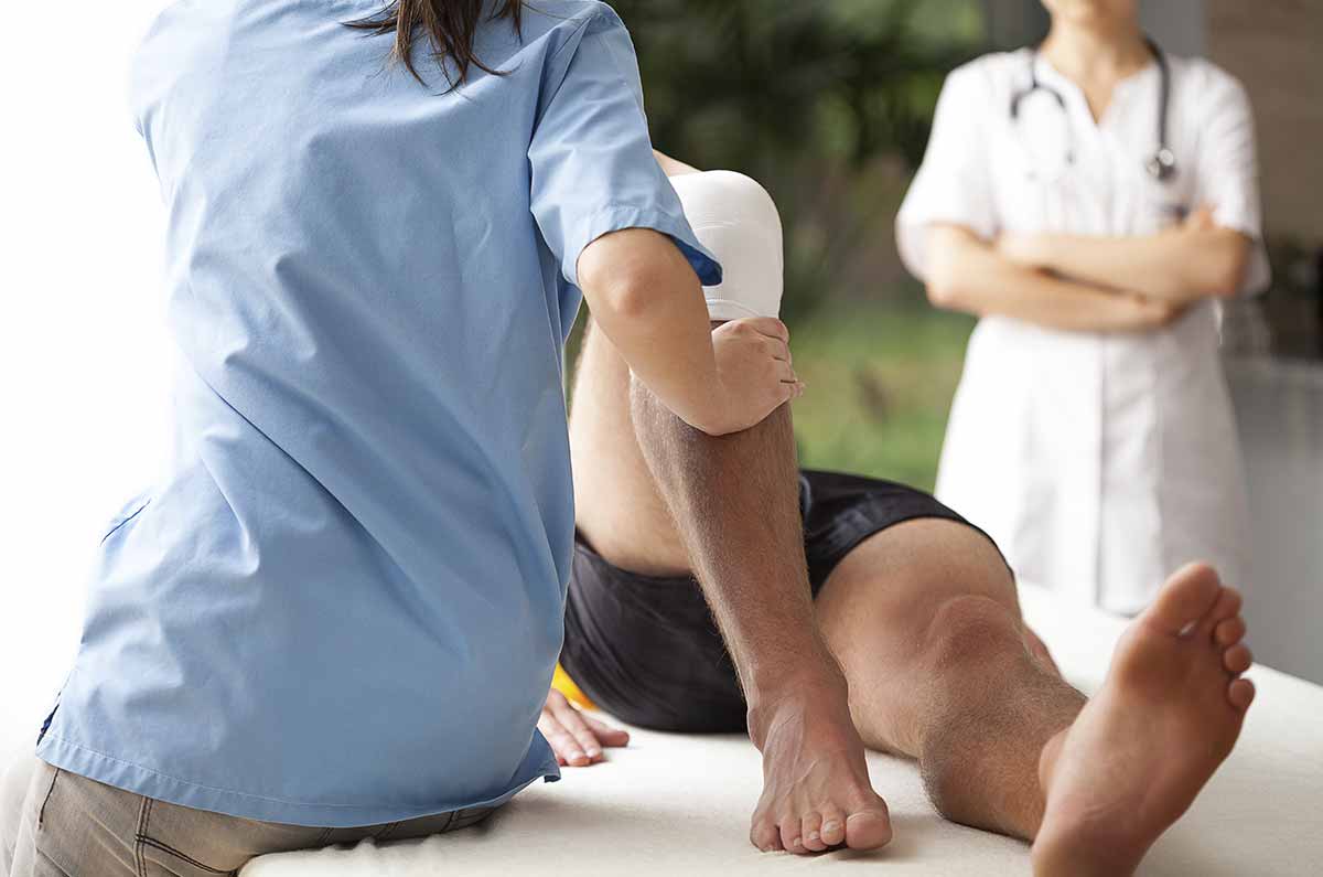 physical therapist bends a reclining patient's knee