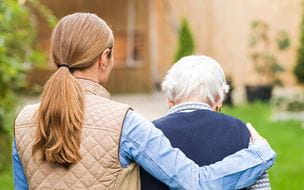 Young carer walking with the elderly woman in the park