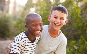 Two boys embracing and laughing hard outdoors