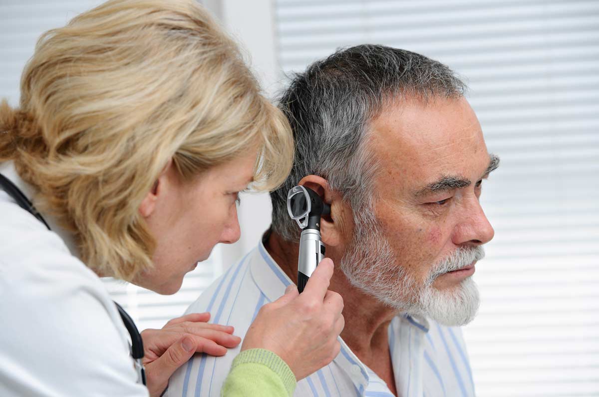 doctor looking inside man's ear with instrument