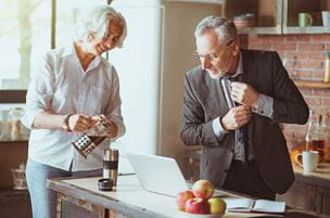 Pleasant older man on the way to work, standing in the kitchen with his wife;