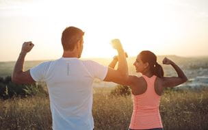Couple of athletes flexing biceps towards the sunset