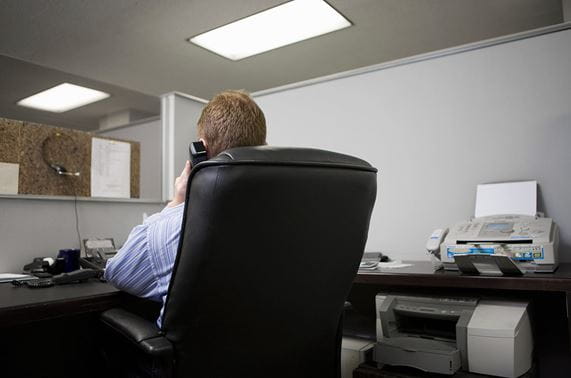 man sitting in office chair on the phone