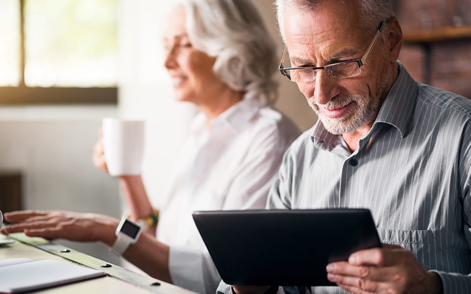 Older couple looking at a tablet and drinking coffee