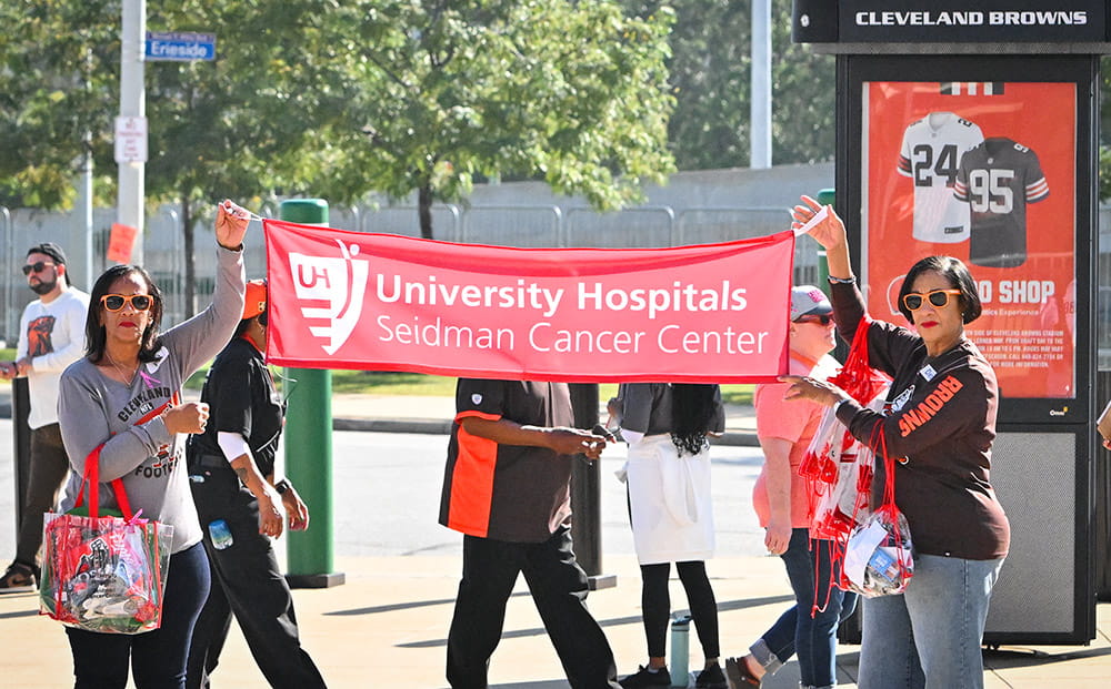 Two women hold a UH Seidman Cancer Center banner outside Browns Satdium. Courtesy David Sands Photography