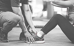 A personal trainer is holding a woman's feet as she exercises