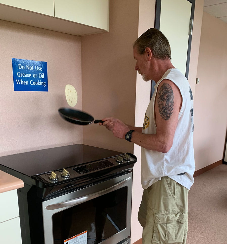 Phil May 2019: A patient flips a tortilla in the neuropsych rehab kitchen.