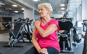Senior woman with pain in shoulder at rehab club