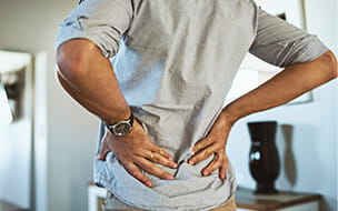 Rearview shot of a man holding his lower back in discomfort due to pain