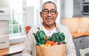 Shot of a elderly man holding a grocery bag in the kitchen